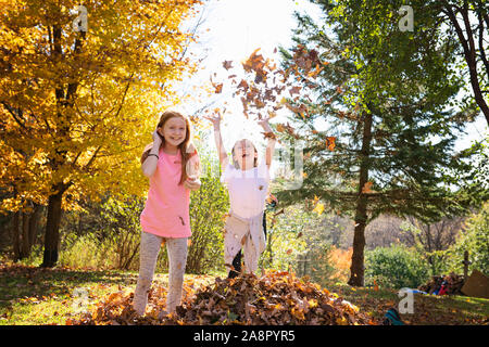 Due giovani ragazze giocando in foglie di autunno Foto Stock