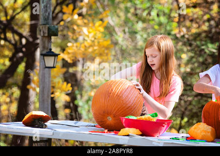 Giovani dai Capelli rossi ragazza intaglia una zucca all'aperto Foto Stock