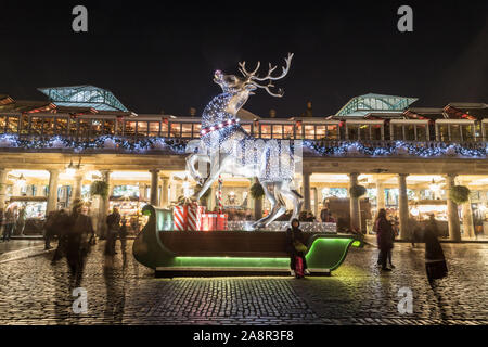 LONDON, Regno Unito - 17Novembre 2018: un grande e decorata renne al Covent Garden di Londra di notte. La gente può essere visto. Foto Stock