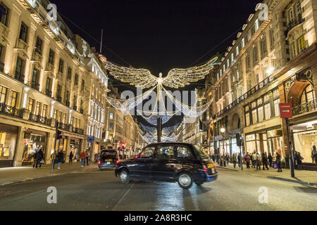 LONDON, Regno Unito - 17Novembre 2018: Viste lungo Regent Street di notte che mostra le decorazioni di Natale lungo la strada. Un tipico London Black Cab può essere Foto Stock