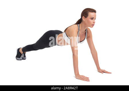 Giovane donna in abbigliamento sportivo facendo esercizi isolato su bianco Foto Stock