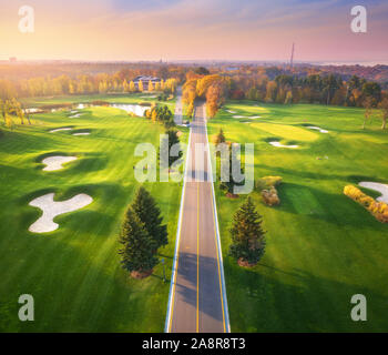 La strada attraverso il campo da golf al tramonto in autunno. Vista aerea Foto Stock