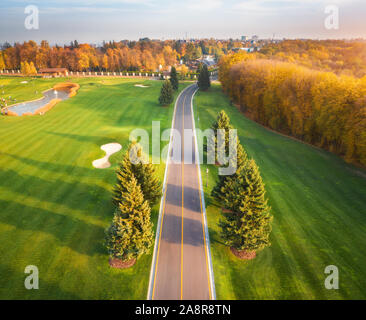 La strada attraverso il campo da golf al tramonto in autunno. Vista aerea Foto Stock