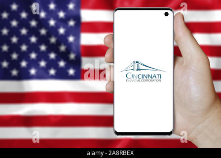 Il logo della società pubblica Cincinnati Financial visualizzata su uno smartphone. Bandiera degli Stati Uniti sullo sfondo. Credito: PIXDUCE Foto Stock