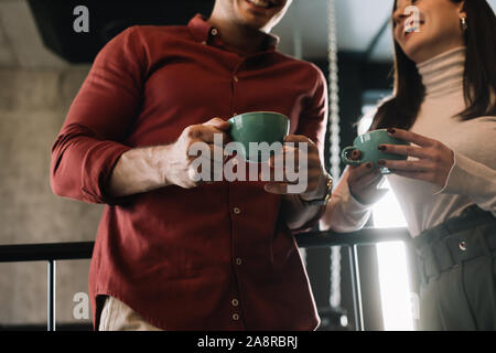 Vista ritagliata della coppia felice di parlare mentre si beve il caffè sul balcone in coffee shop Foto Stock