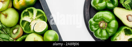 Panoramica di kiwi freschi, tigli, peperoni, mele, avocado in una scatola di legno e pizza pan Foto Stock