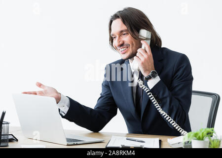 Happy businessman parlando al telefono e guardando il computer portatile Foto Stock