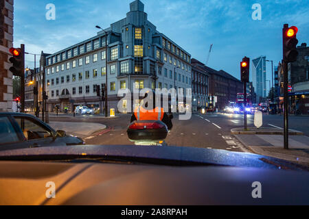 Consegna bike rider guida attraverso le strade della città di Londra all'alba Foto Stock