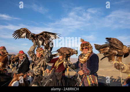 Un gruppo di tradizionale kazako cacciatori eagle mantenendo le loro aquile reali a cavallo. Ulgii, Mongolia. Foto Stock