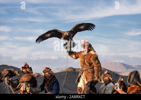 Un gruppo di tradizionale kazako cacciatori eagle mantenendo le loro aquile reali a cavallo. Ulgii, Mongolia. Foto Stock