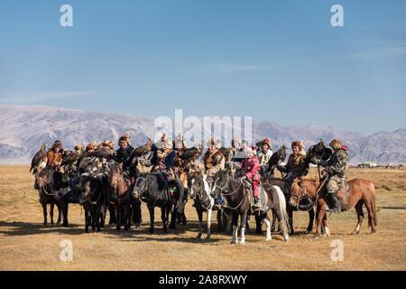 Un gruppo di tradizionali aquila kazaka cacciatori in posa con loro le aquile reali a cavallo. Ulgii, Mongolia. Foto Stock