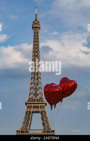 A forma di cuore rosso metallico palloncini davanti alla torre eiffel con cielo blu e alcune soffici nuvole Foto Stock