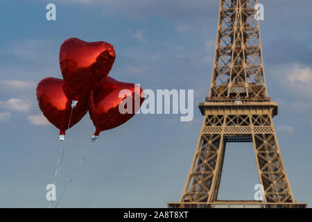 A forma di cuore rosso metallico palloncini davanti alla torre eiffel con cielo blu e alcune soffici nuvole Foto Stock