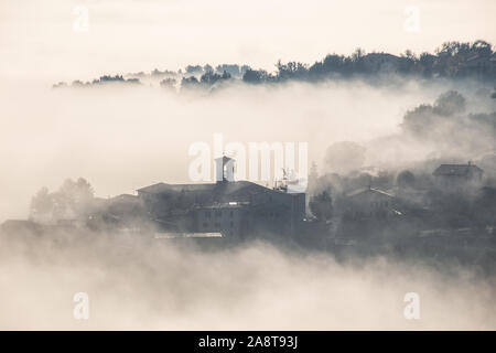 Surreale in vista di una piccola città in Umbria (Italia) quasi completamente nascosto dalla nebbia Foto Stock