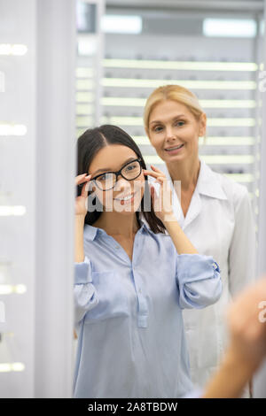 Dai capelli scuri imprenditrice cercando belle occhiali in negozio OTTICA Foto Stock