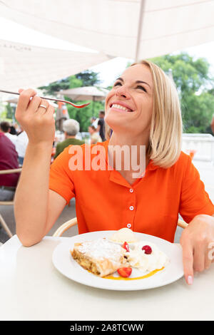 Giovane donna si siede in un Caffè di Vienna e Austria mangia il dolce tradizionale strudel di mele con panna montata e gelato alla vaniglia, Vienna, Austria Foto Stock