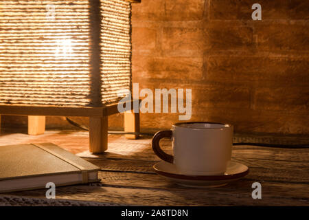 Tazza di caffè, notebook e vintage lampada da tavolo. Tempo per rilassarsi. Foto Stock