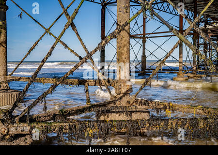 Sotto il Boardwalk e tra i lavori in ferro sotto Cromer Pier sulla costa di Norfolk Foto Stock