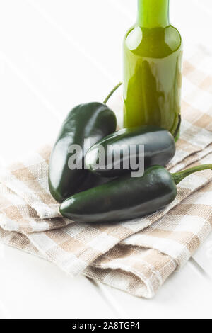 Verde peperoncino jalapeno e salsa Tabasco sul tovagliolo a scacchi. Foto Stock