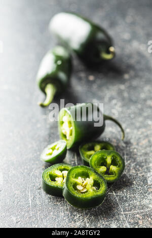 Affettato verde peperoncino jalapeno sul vecchio tavolo da cucina. Foto Stock