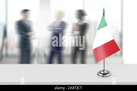 Bandiera Italiana è in piedi su un palo metallico è in ufficio tavolo mentre di politici o di uomini d'affari, imprenditrice a discutere di una questione a livello di sfondo. 3D Foto Stock