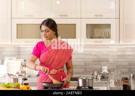 Donna in saree cucina in cucina Foto Stock
