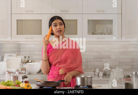 La donna in cucina pensando di stoviglie Foto Stock