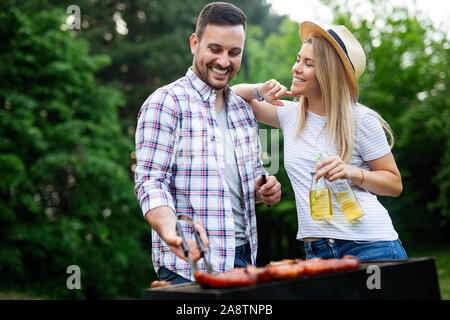 Coppia giovane la preparazione di salsicce su un barbecue all'aperto Foto Stock