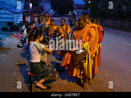 I monaci in abiti dello zafferano nelle strade all'alba nel Patrimonio Mondiale elencati città Luang Prabang in Laos la mattina alms dando cerimonia o Tak Bak Foto Stock