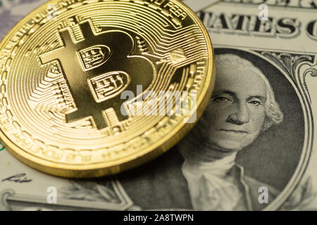 Golden Bitcoin cryptocurrency coin che copre l'immagine di George Washington in un US Dollar banconota Foto Stock