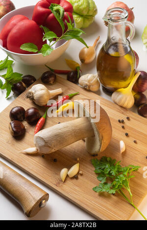 In autunno i doni della natura sul tavolo con tagliere. Selezione di funghi, castagne, spezie, paprica, aglio, cipolle, chayote, melograno e olive Foto Stock