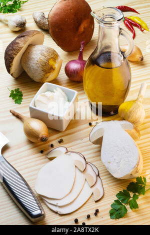 Fette di penny bun per fungo carpaccio sulla tabella laden con spezie, olio d'oliva, aglio, cipolle e funghi. Cep, porcino, Boletus edulis Foto Stock