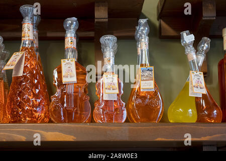 Ornati in bottiglie di vetro di San Spiridione kumquat liquore per la vendita in un cibo e vino shop sull'isola greca di Corfù. Foto Stock