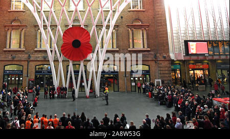 Le persone si radunano per osservare un silenzio per contrassegnare il giorno dell'Armistizio, anniversario della fine della Prima Guerra Mondiale, a King's Cross St Pancras Station di Londra. Foto Stock