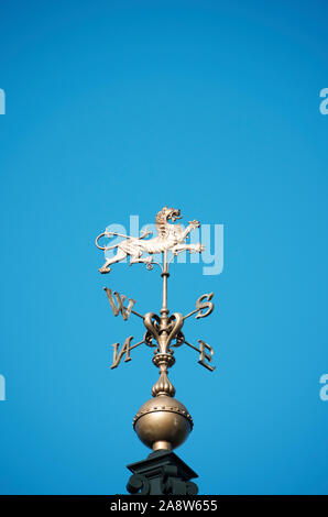 Ottone banderuola feroce con lion splendente d'oro brillante nel cielo blu Foto Stock