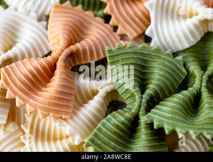 Farfalle close up macro mostra strappato pasta di prua, tri-colore messa a fuoco selettiva di sfondo per copia di spazio o di sovrapposizione di testo Foto Stock