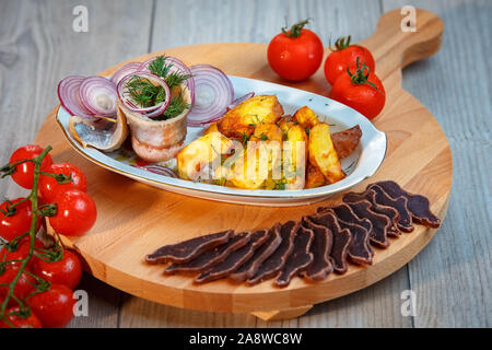 Still Life - Aperitivo per birra, aringa, Salumi, pomodori ciliegini, patate rustiche Foto Stock