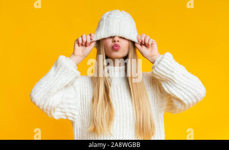 Ragazza con baciare le labbra tirando verso il basso cappello di lana Foto Stock