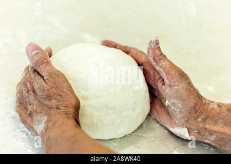 Le mani delle donne rendendo per impastare la pasta per gnocchi Foto Stock