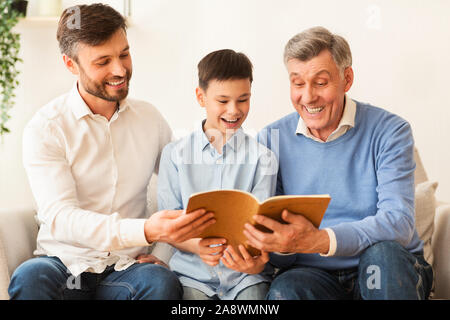Felice ragazzo lettura prenota con il papà e il Nonno a casa Foto Stock