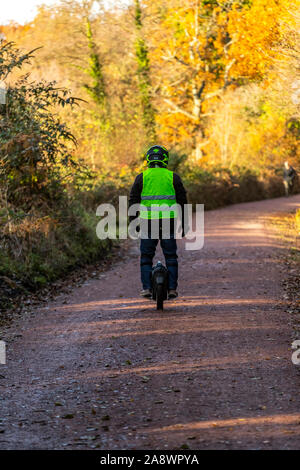 Un uomo che cavalca un monociclo elettrico lungo una ex ferrovia linea adesso un cycleway a Cannop stagni, Foresta di Dean. Autunno Foto Stock