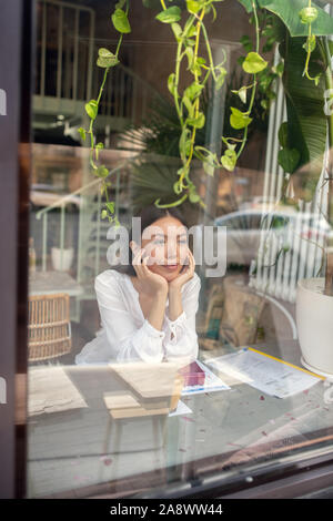 Sentimento donna annoiati durante l'attesa per il collega in caffetteria Foto Stock