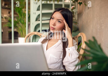 Imprenditrice avente mal di testa dopo il lavoro per un periodo di tempo troppo lungo Foto Stock