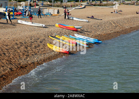 Schede madri per il surf, canoe e barche a vela e la gente si vede sulla spiaggia di Dover in un giorno caldo e soleggiato alla fine di settembre. Foto Stock