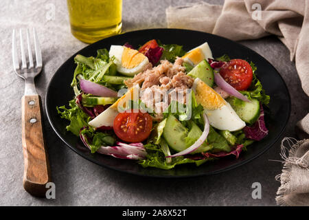 Con insalata di tonno, uova e verdure sulla piastra nera e lo sfondo grigio Foto Stock