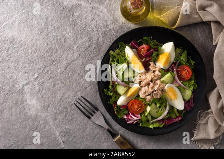 Con insalata di tonno, uova e verdure sulla piastra di nero e grigio. Vista dall'alto. Spazio di copia Foto Stock