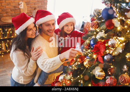 La famiglia felice decorazione di albero di Natale con le bollicine nel soggiorno Foto Stock