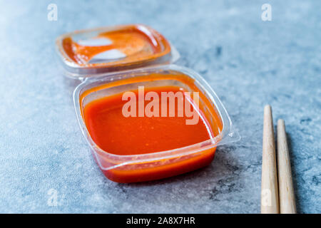 Caldo rosso piccante salsa Sriracha in scatola di plastica / confezione o contenitore per il Fast Food pronto a mangiare. Cibo tradizionale salsa. Foto Stock