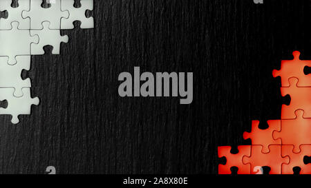 Il bianco e il rosso puzzle negli angoli su un nero ardesia sullo sfondo di pietra. I colori che appaiono sulle bandiere: Polonia, Austria, Bahrein, Danimarca, Indonesi Foto Stock