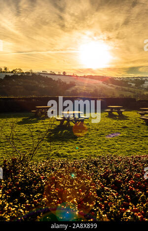 Tramonto su alcuni tavoli da picnic nella gloriosa Derbyshire Peak District National Park, tabelle vuote su un gelido freddo Gennaio sera al tramonto Foto Stock